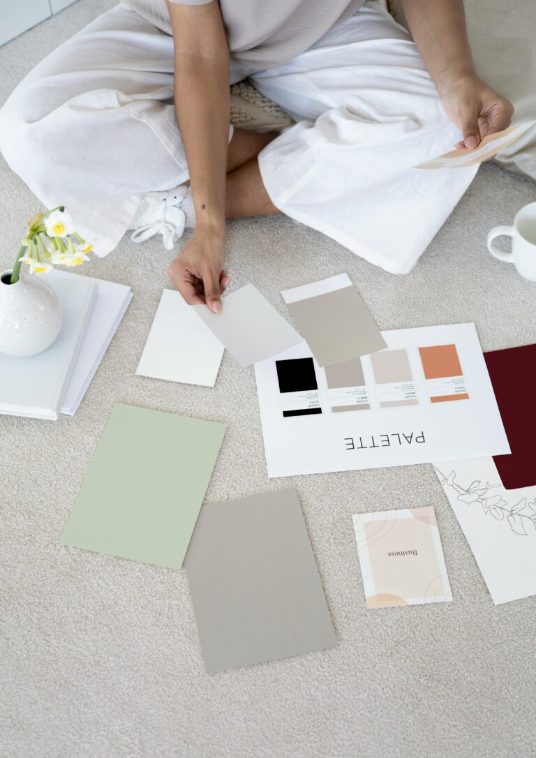 Designer sits on carpet with color palettes and samples, planning creative project.